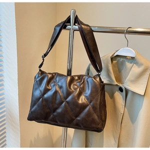 Detail of dark brown quilted crossbody bag with soft faux leather and wide shoulder strap