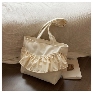 Detail of cream canvas tote bag with ruffled pleated trim and wide shoulder straps