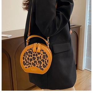 Detail view of round leopard print crossbody bag with high-quality stitching and metal zippers
