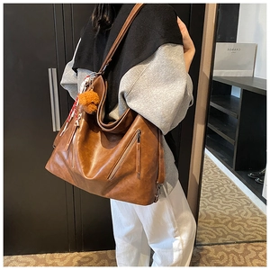 Dettaglio di una borsa tote in pelle marrone con ciondolo a forma di orso