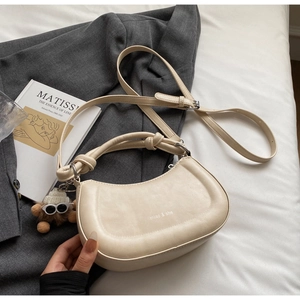 Detail der beigen Satteltasche aus Kunstleder mit Knotengriff und Plüschkugel-Anhänger