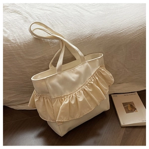 Detail of off-white canvas tote bag featuring stylish ruffled pleats and long handles