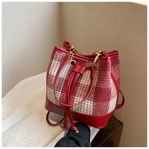Détail du sac seau à carreaux rouges avec cordon de serrage et garniture dorée