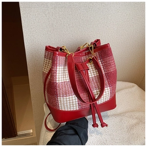 Détail du sac seau à carreaux rouge et blanc avec finitions en cuir et cordon