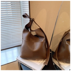 Close-up of brown matte leather hobo bag with front pockets and shoulder strap detail