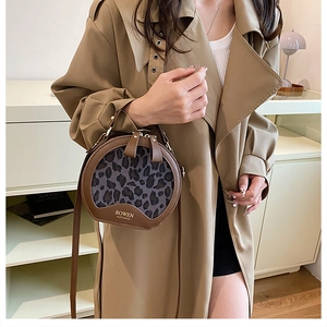 Detail view of round leopard print crossbody bag with premium leather handles and branding
