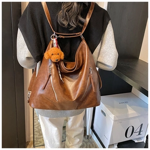 Zaino vintage in pelle marrone indossato sulla schiena con ampie tasche anteriori