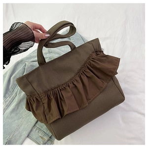 Detailed close-up of brown canvas tote bag with decorative ruffle trim and sturdy handles