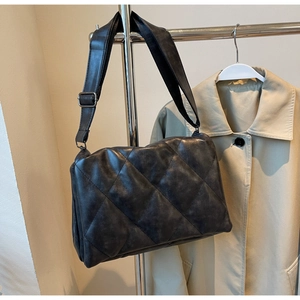 Detail of black quilted puffer shoulder bag with soft texture and adjustable strap