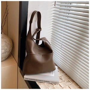 Detail of dark brown leather hobo bag with fine stitching and golden metal buckle