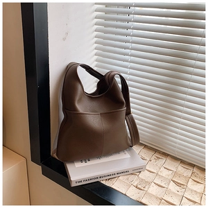 Detail of dark brown matte leather hobo bag with vertical stitching under striped lighting