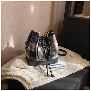 Détail d'un sac seau en tweed tricolore avec finitions en cuir noir et cordon de serrage