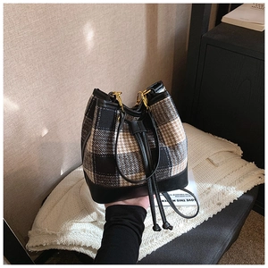 Détail du sac seau en tweed avec motif à carreaux tricolore et finitions dorées