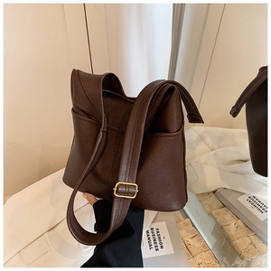 Detail of retro dark brown shoulder bag featuring an outer pocket and adjustable gold buckle