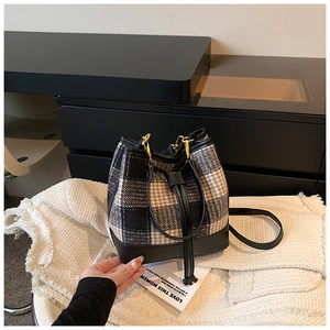 Détail du sac seau à carreaux avec texture en tweed et fermeture à cordon en cuir noir