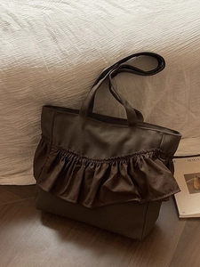 Brown canvas tote bag featuring large ruffles and a spacious design for women