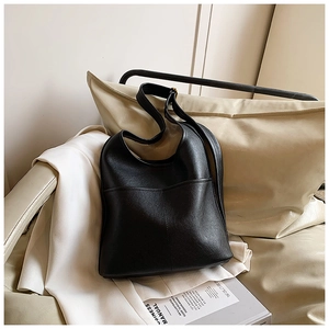 Close-up of black lychee grain leather hobo bag with gold hardware on a sofa