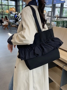 Fashionable black ruffled tote bag with large capacity for women shown on shoulder
