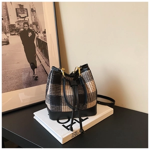Vue détaillée d'un sac seau à carreaux avec base en cuir noir et crochets dorés chics