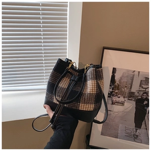 Détail du sac seau à carreaux avec garniture en cuir noir et cordon de serrage doré