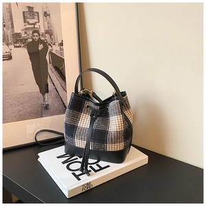 Détail du sac seau à carreaux avec cordon de serrage et finitions dorées sur livres