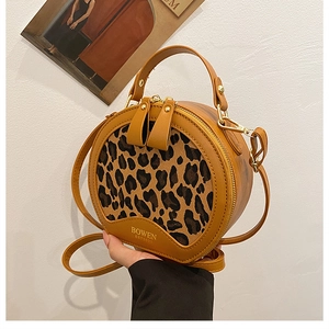 Detail of round leopard print crossbody bag with yellow leather trim and double zippers