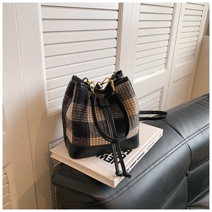 Vue détaillée d'un sac seau vintage en tweed avec garniture en cuir noir et crochets dorés