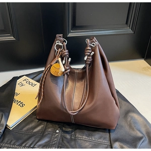 Detail of dark brown leather hobo bag with white stitching and knotted handle design