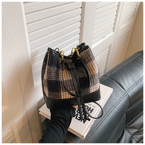 Détail du sac seau à cordon en tissu écossais noir et marron avec garniture en cuir
