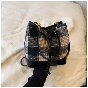 Détail du sac seau rétro à carreaux avec fermeture à cordon et base en cuir noir