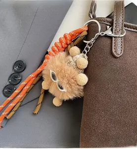 Détail d'un porte-clés en peluche marron avec lunettes sur un sac à main en cuir texturé