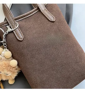 Détail d'un sac à bandoulière en daim marron avec un joli pendentif ours en peluche