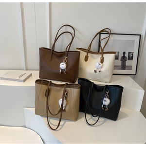Detail view of large tote bags in four colors with plush charms on geometric display