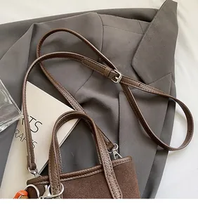 Détail du sac bandoulière vintage léopard avec lanières en cuir et breloque tissée décorative