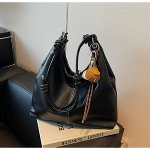 Detail of black leather hobo bag featuring white contrast stitching and a knotted strap