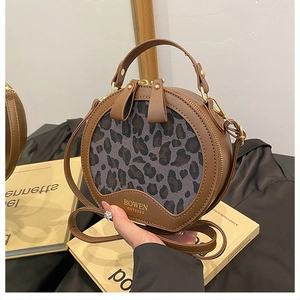 Close-up of leopard print round handbag with dual gold zippers and BOWEN branding