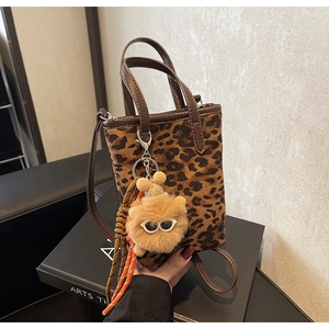 Détail d'un mini sac cabas léopard avec pendentif monstre et poignée en cuir