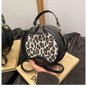 Detail view of round leopard print crossbody bag on book prop with mirror reflection