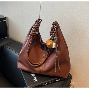 Close-up of brown PU leather tote bag with white contrast stitching and knotted handle