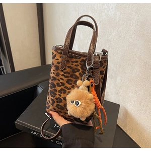 Gros plan du mini sac fourre-tout léopard avec breloque monstre en peluche et anses en cuir