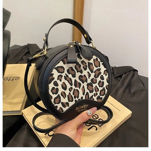 Detailed close-up of a leopard print round bag featuring BOWEN gold text and metal hardware