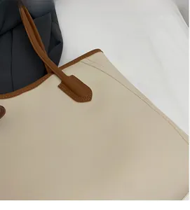 Detail of minimalist cream tote bag with brown shoulder strap and reinforced stitching