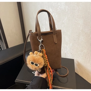 Détail du mini sac en daim marron foncé avec breloques en peluche et tissées