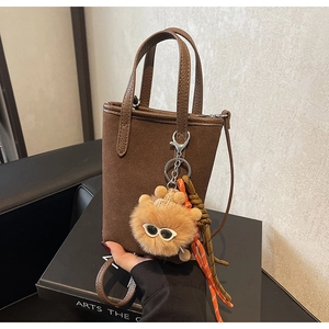 Gros plan du mini sac cabas marron en daim avec motif léopard et breloque ours mignon