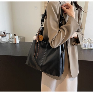 Close-up of black tote bag with white contrast stitching and cute baseball bear charm