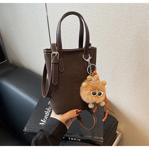 Détail d'un sac seau vintage léopard mat avec breloque peluche et fermoir métallique