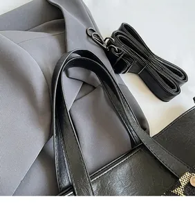 Detail of adjustable black pebble leather strap and metal hooks on a large tote bag