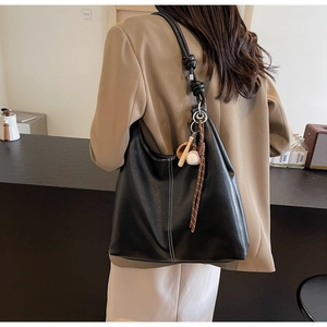 Detail of black leather tote bag with white contrast stitching and a knotted shoulder strap