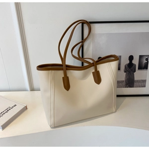 Detail of minimalist tote bag with cream leather texture and brown handle trims