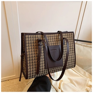 Detail of houndstooth woven fabric and brown leather pocket on a large tote bag